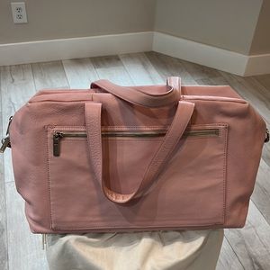 Away The Everwhere Bag in pink leather with shoulder strap and dust cover.